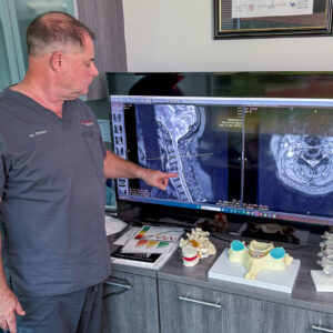 chiropractor Dr. David Packer examining neck MRI images on a large screen