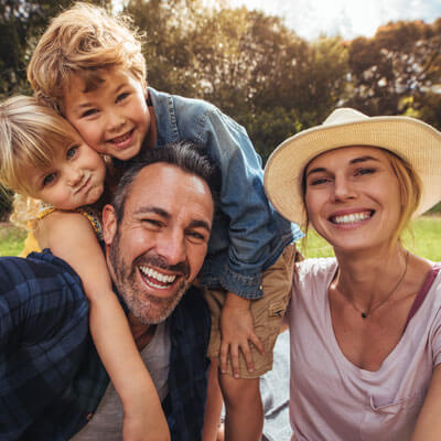 Family of four smiling together outdoors in a park