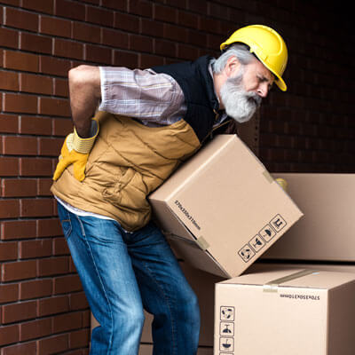 Man lifting a heavy box and holding his lower back in pain
