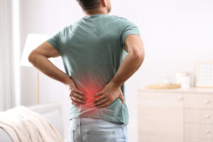 Man holding his lower back with red highlight indicating area of back pain
