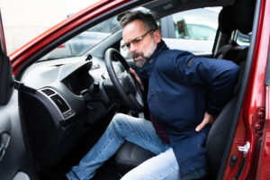 Man experiencing lower back pain while getting out of a car after an auto accident