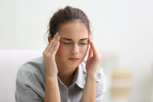 Portrait of young woman suffering from headache at home Young woman holding her head experiencing a chronic headache