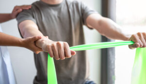 Doctor or Physiotherapist working examining treating injured arm of athlete male patient, stretching and exercise, Doing the Rehabilitation therapy pain in clinic patient doing rehabilitation exercises guided by a therapist